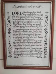 Framed calligraphy artwork titled '17th Century Nun's Prayer,' featuring ornate hand-lettered text bordered by illustrated birds and floral motifs, mounted in a wooden frame