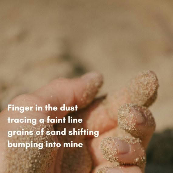 Finger in the dust tracing a faint line grains of sand shifting bumping into mine